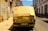 A yellow van with cardboard covering the windshield, parked on a narrow cobblestone street lined with old, weathered buildings. Graffiti is visible on the left wall, and the van bears a license plate marking it as registered in Lisbon.