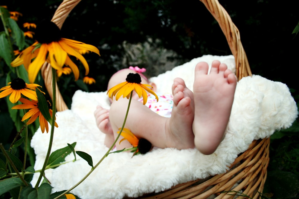 A barefoot baby on a soft blanket in a wicker basket