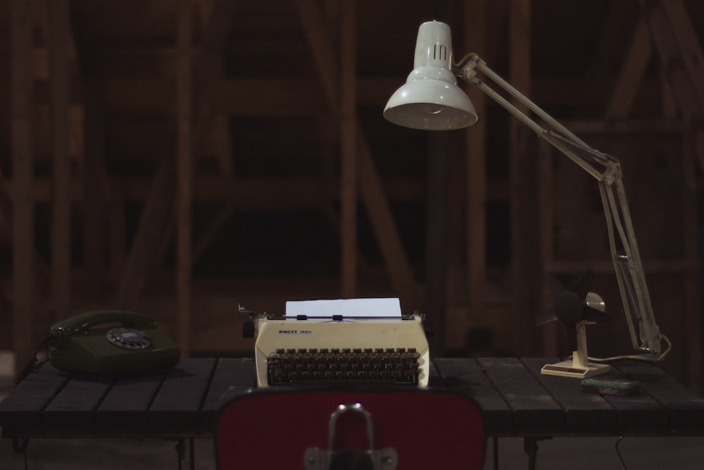 Machine à écrire blanche et noire à côté du téléphone sur une table brune