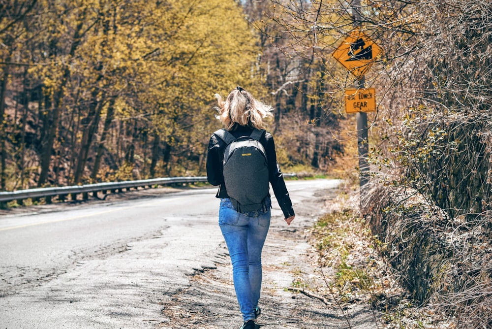 person walking on pethway between green leafed trees