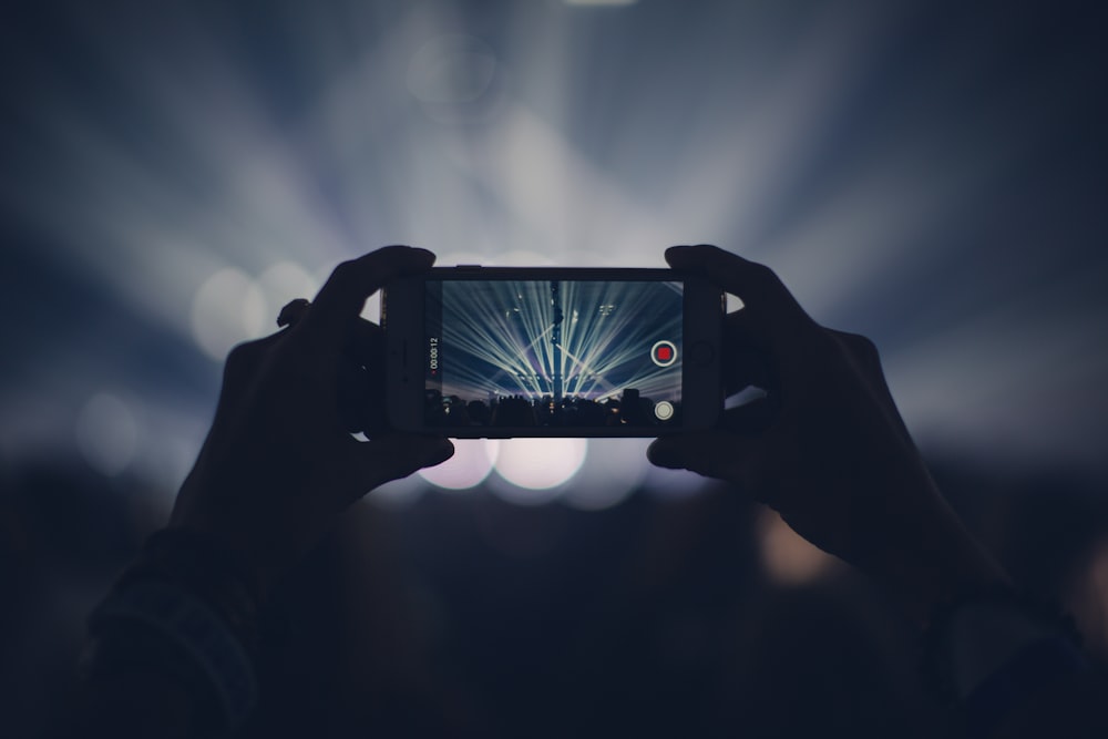 person taking video of live concert