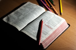 An open Bible with a pen and musical notes scattered around.