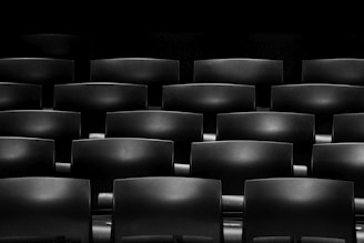 Minimalist black and white photo of neatly arranged modern tables and chairs set for an event.