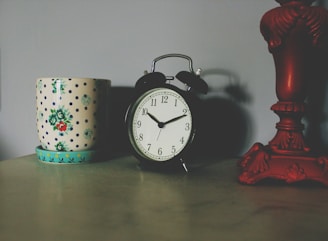 black table clock beside ceramic vase