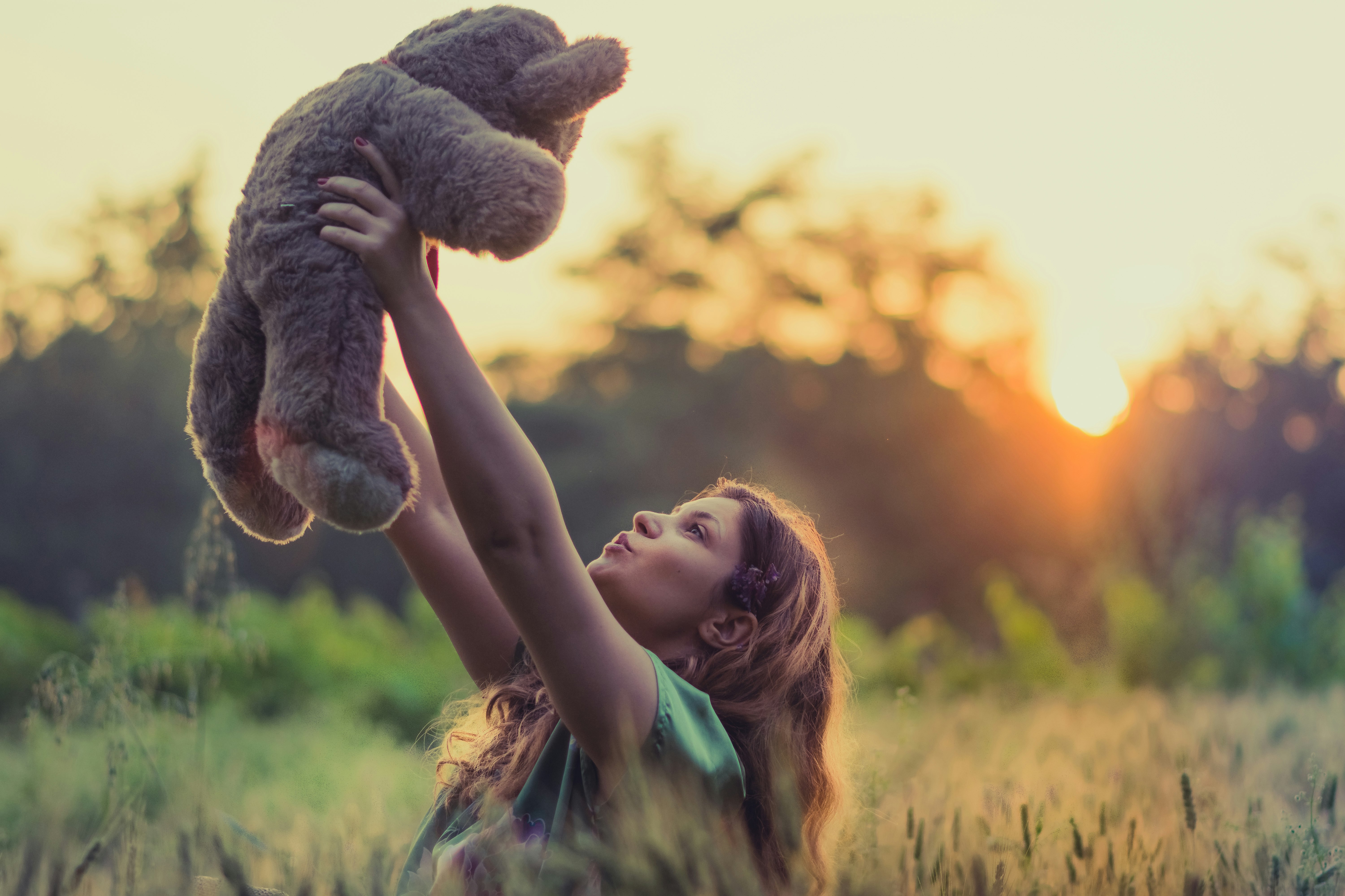 woman lifting brown bear plush toy