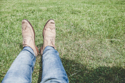 A pair of sturdy knee pads lying on a grassy field under sunlight.