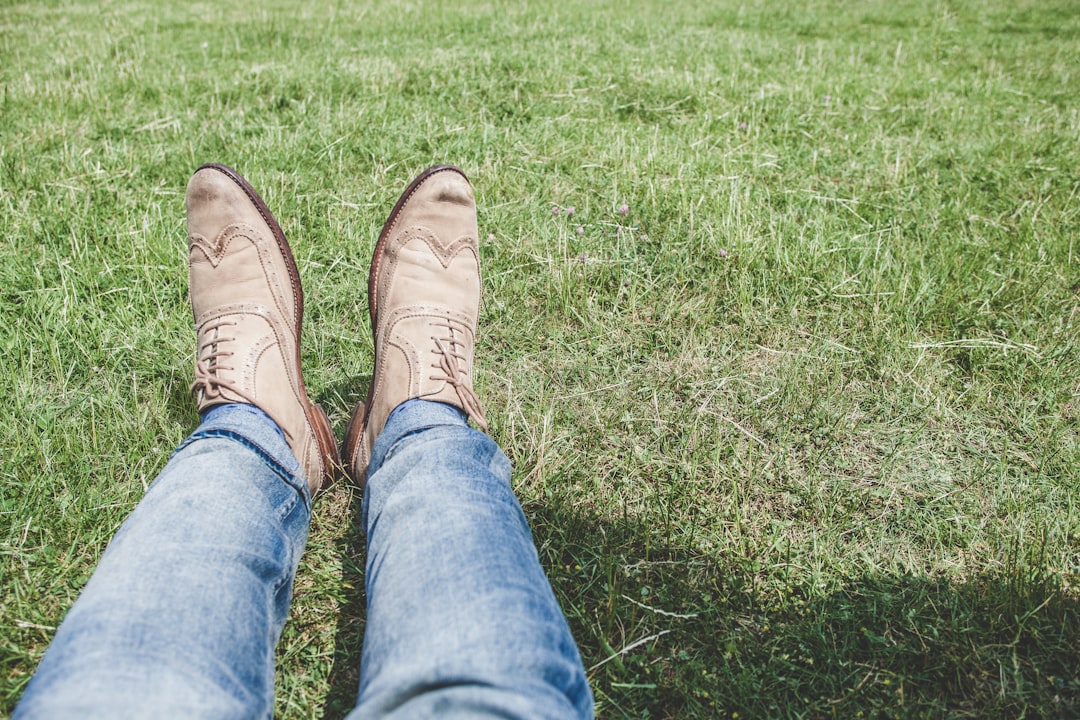 person wearing blue jeans and pair of white shoes