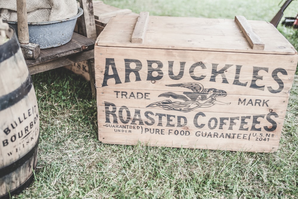 brown wooden storage box beside barrel on grass field