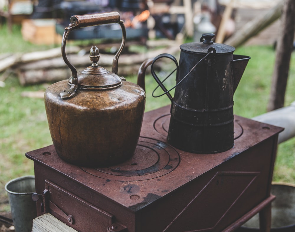 two brown and gray teapots on top of brown box