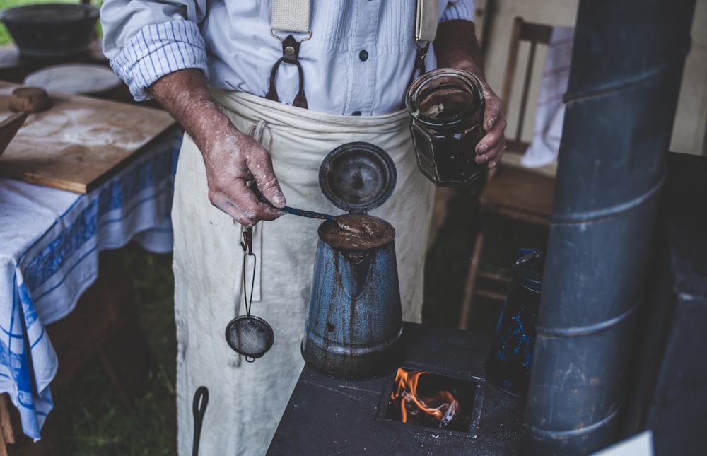 man standing while holding can and jar