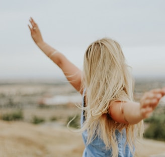 woman wearing blue top while standing on plain field