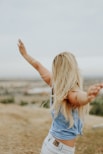 woman wearing blue top while standing on plain field