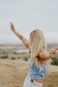 woman wearing blue top while standing on plain field