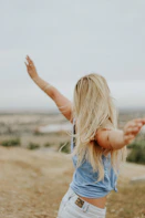 woman wearing blue top while standing on plain field