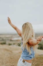 woman wearing blue top while standing on plain field and feeling free