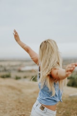woman wearing blue top while standing on plain field