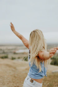woman wearing blue top while standing on plain field