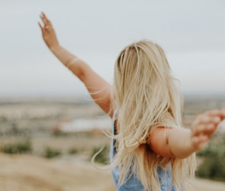 woman wearing blue top while standing on plain field