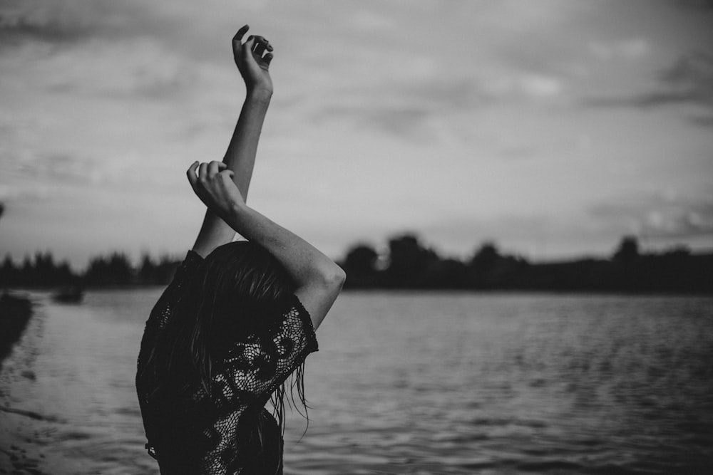 grayscale photo of woman stretching body front of body of water