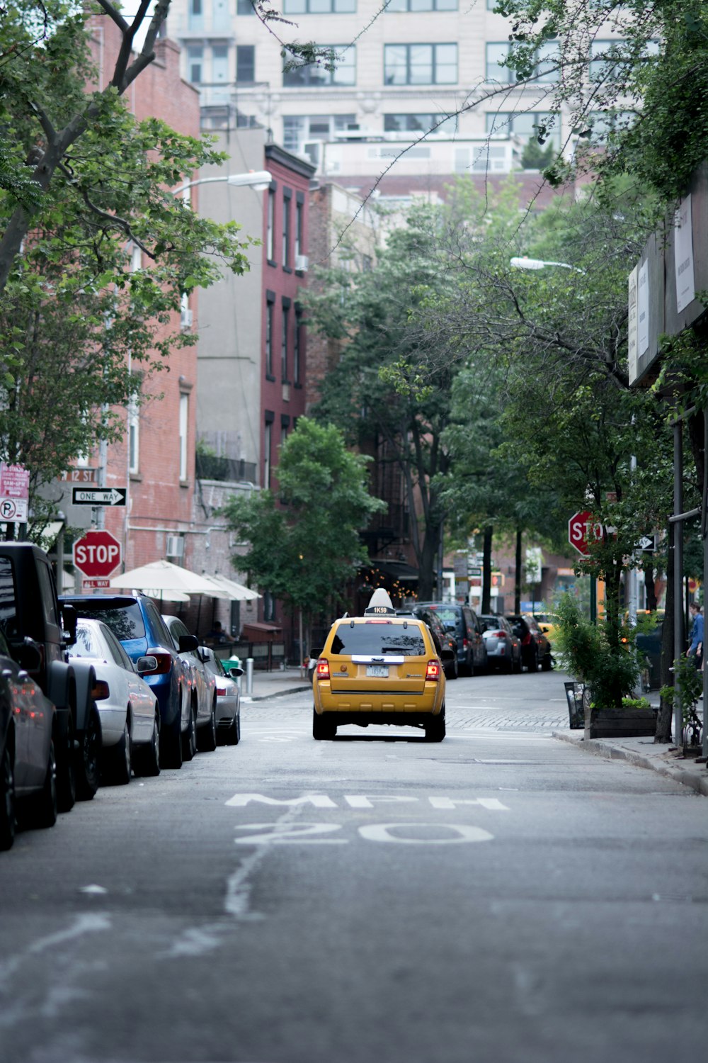 Taxi amarillo en la parte superior de la carretera de concreto gris cerca de edificios y árboles durante el día