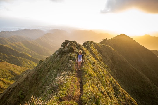 woman walking on pathway on top of hill at golden hour in Haiku Stairs United States