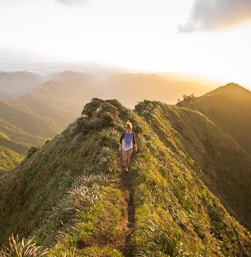 woman walking on pathway on top of hill at golden hour