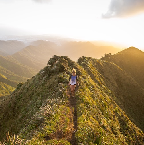 woman walking on pathway on top of hill at golden hour