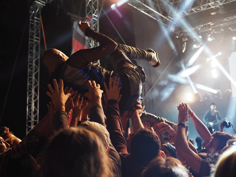 group of people carrying a person in front of the concert stage