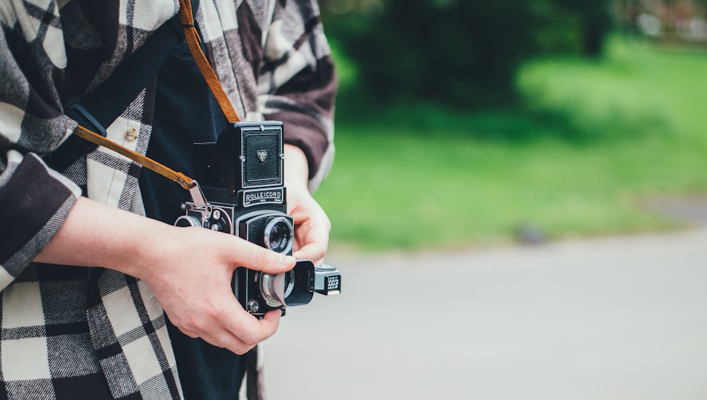 pessoa carregando câmera DSLR em fotografia de foco raso