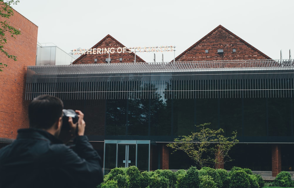 man taking picture to building