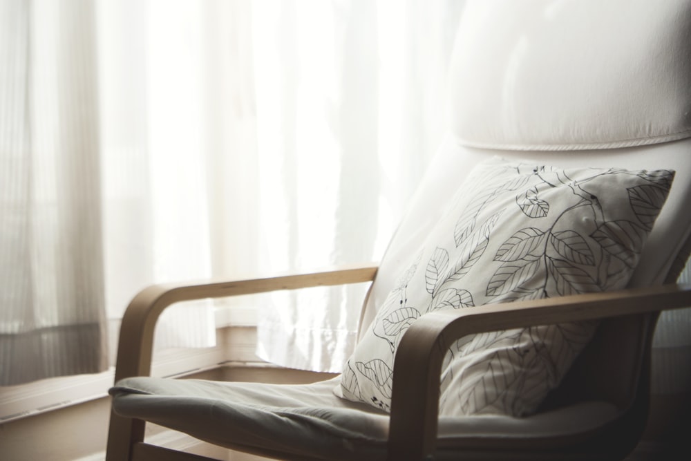 Almohada sobre sillón con estampado de hojas blancas y grises