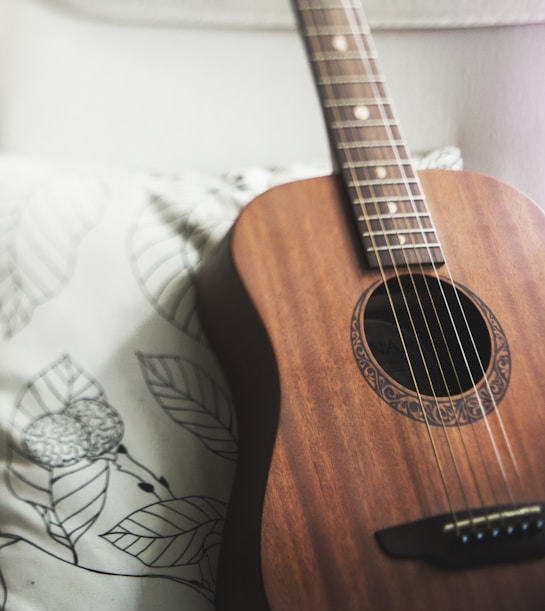 selective focus photo of brown guitar on white pillow