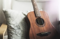 selective focus photo of brown guitar on white pillow