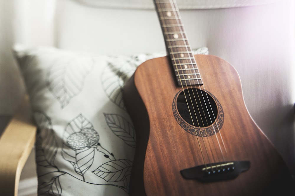 selective focus photo of brown guitar on white pillow