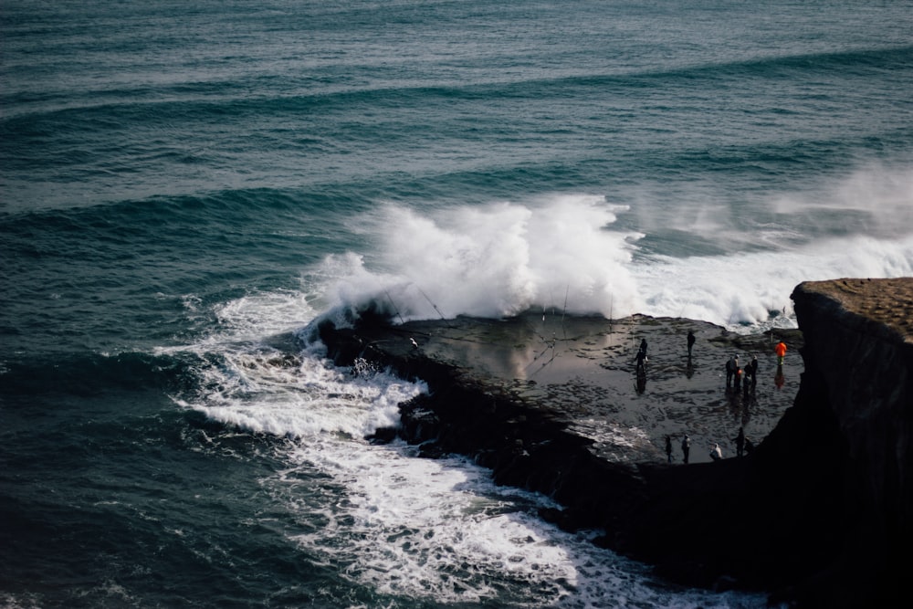 a group of people standing on top of a cliff next to the ocean