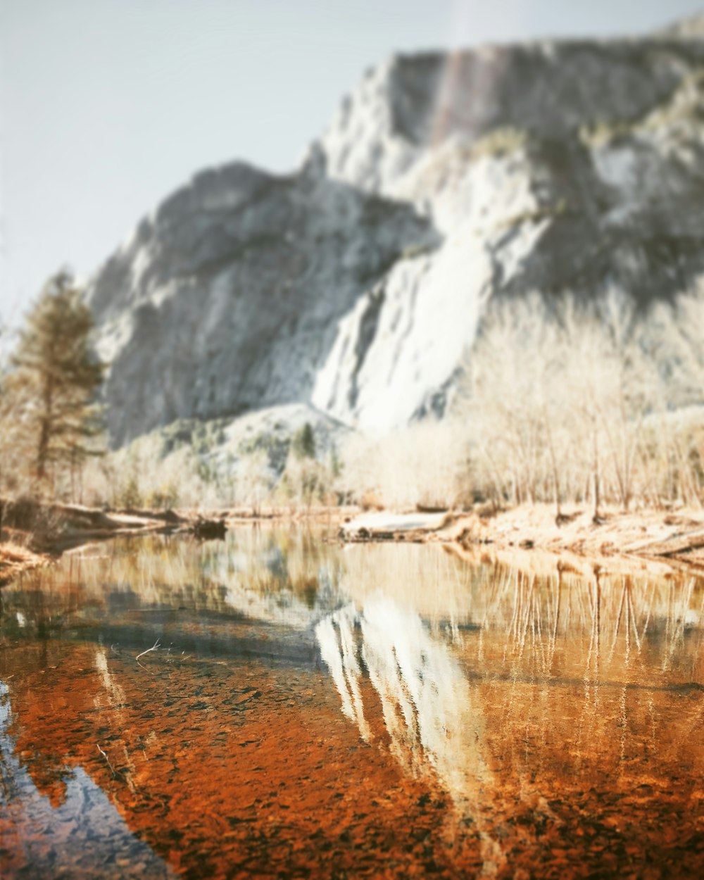 reflection of rock cliff on calm river water