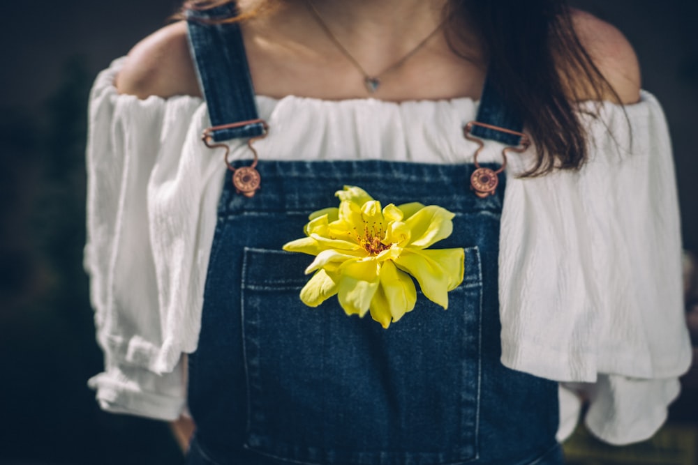 person wearing overalls with yellow petaled flowers on pocket