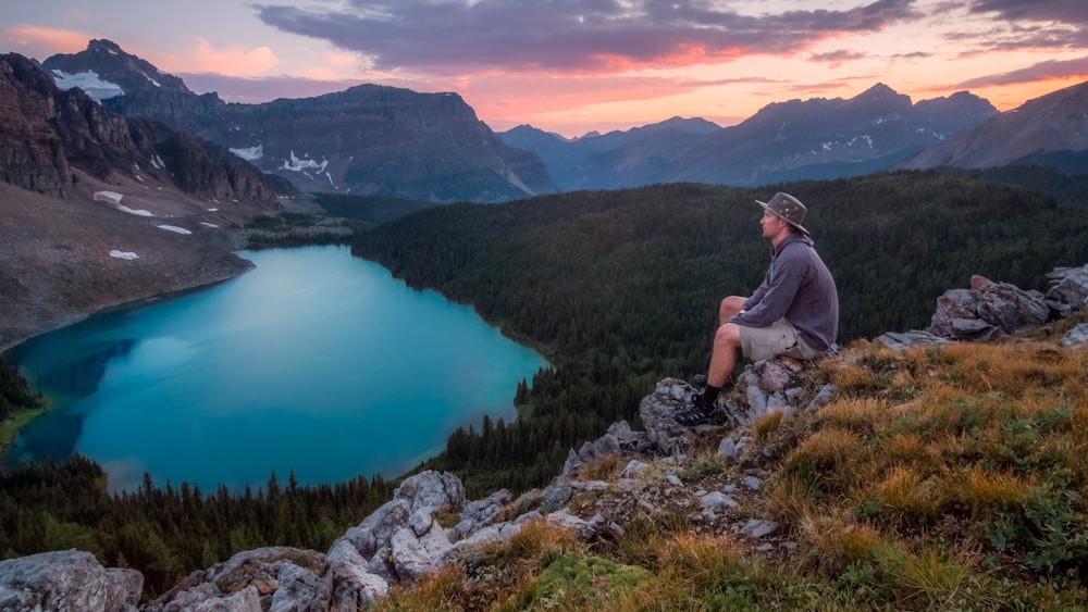 homme regardant sur la montagne assis sur le rocher