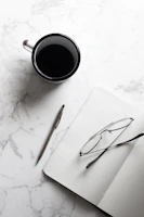 Elegant flat lay of a handwritten note, a black pen, and a cup of coffee on a beige linen surface.