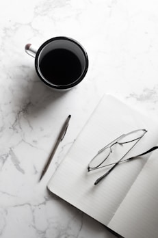 A flat lay of a notebook, pen, and a cup of coffee.