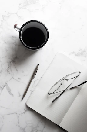 An artistic flat lay of notes, a notebook, and coffee cup resting on a wooden table, symbolizing creativity and focus.