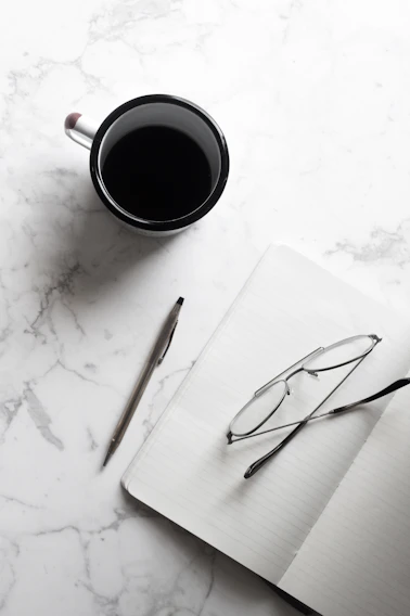 A cozy flat lay of journals, planners, and a cup of tea on a wooden table inviting calm and focus.