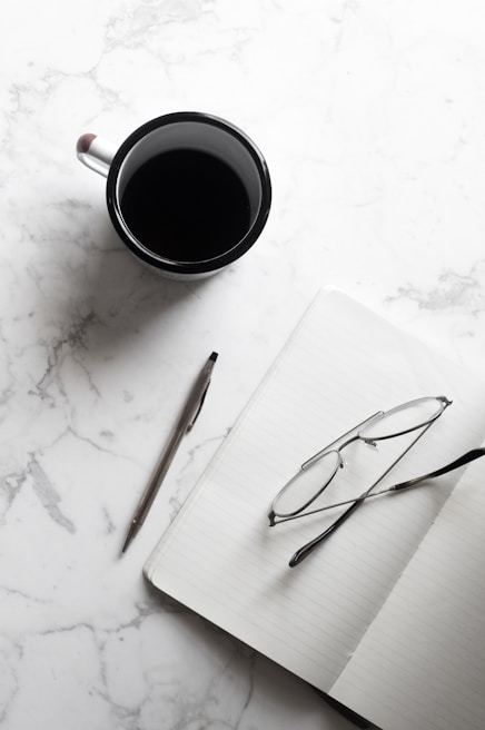 A flat lay of a printed PDF guide next to a cup of coffee and reading glasses on a wooden table.