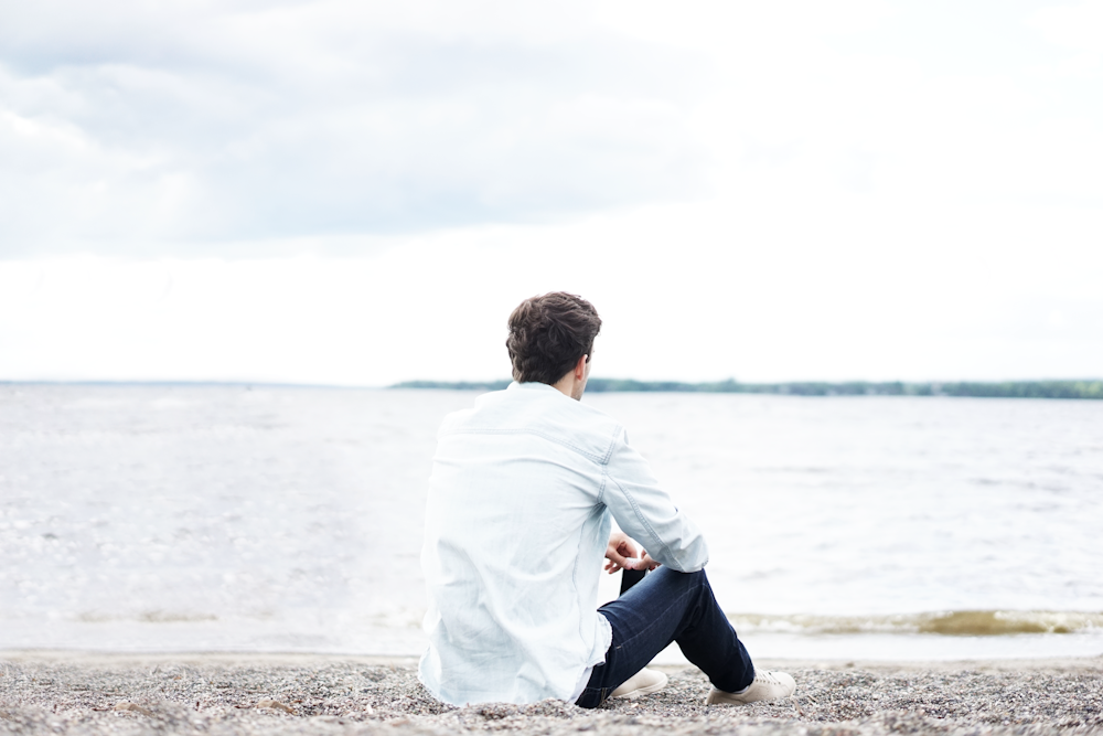 A young man looks out at the water longingly due to his depression