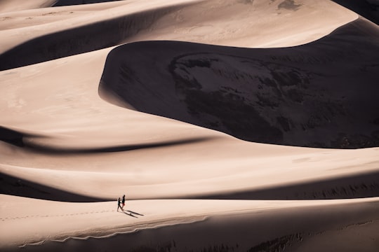 two person walking on desert during daytime in Great Sand Dunes National Park and Preserve United States