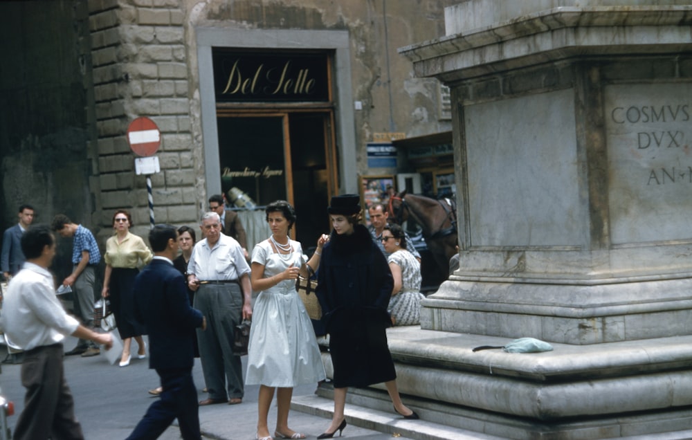 a group of people walking down a street next to a statue