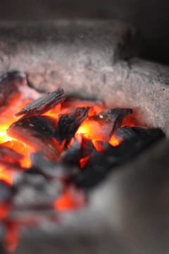 A softly lit charcoal-gray ceramic vessel with a deep ember glow accent.