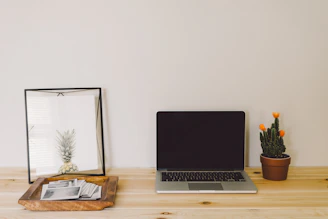 A sleek, minimalist office desk with a laptop, notebook, and a small blue oak tree sculpture symbolizing growth and clarity.