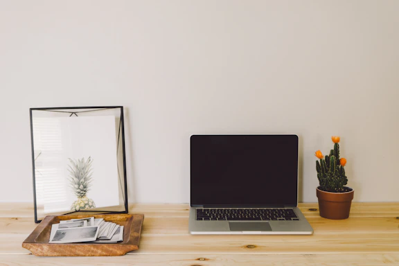 A sleek, minimalist office desk with a laptop, notebook, and a small blue oak tree sculpture symbolizing growth and clarity.