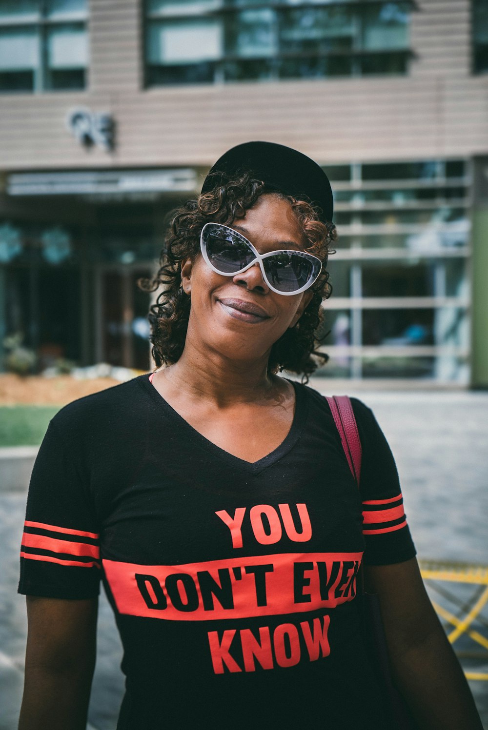 selektive Fokusfotografie einer Frau, die tagsüber ein schwarzes Hemd mit V-Ausschnitt in der Nähe eines Gebäudes trägt